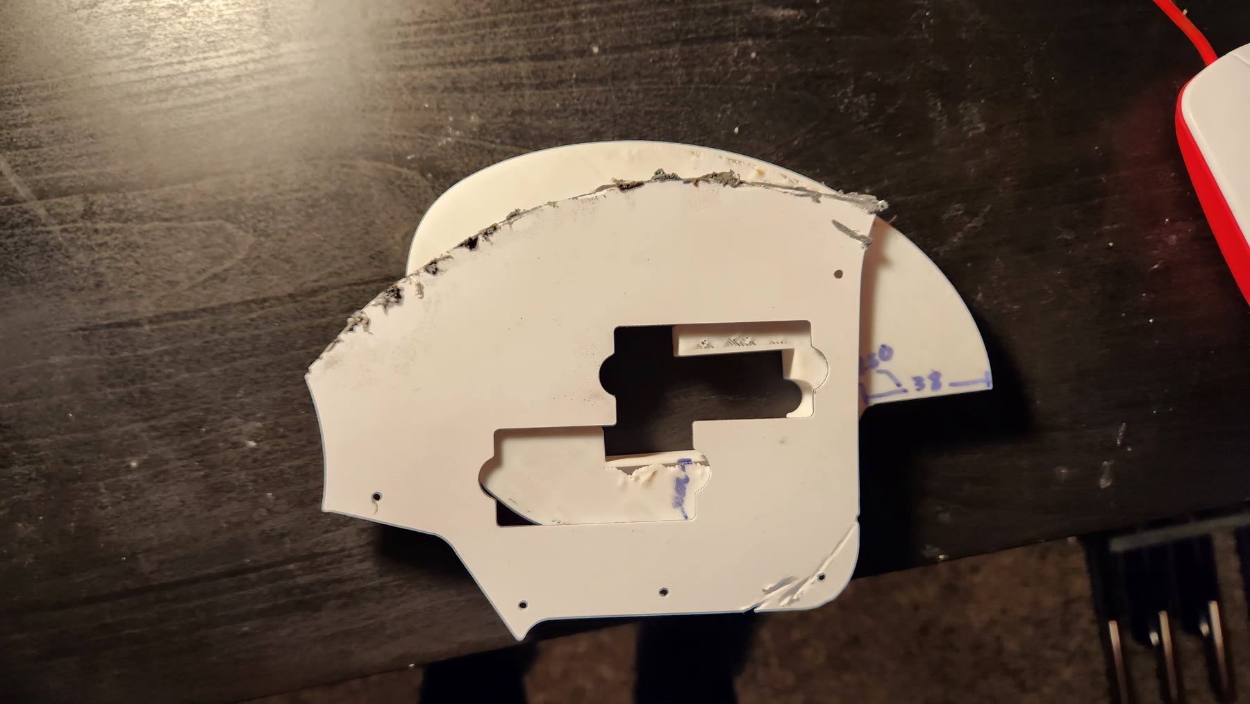 Rough, uneven hand-cut edges on the damaged pearloid pickguard blank